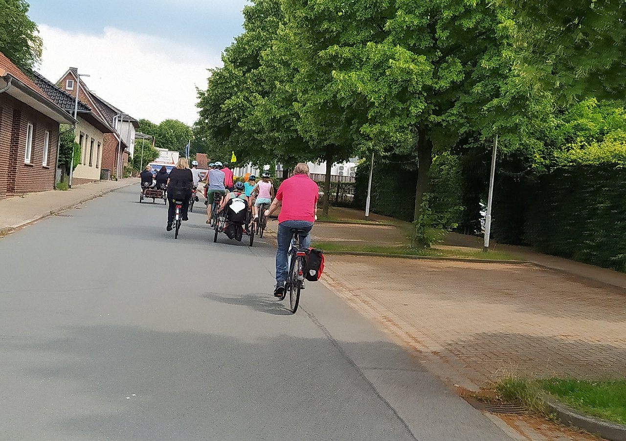 Zu sehen ist eine von hinten aufgenommene Gruppe Radfahrer mit verschiedenen Spezialrädern und Fahrrädern