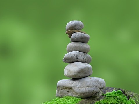 Das Bild zeigt aufeinandergestapelte graue Steine vor grünem Hintergrund