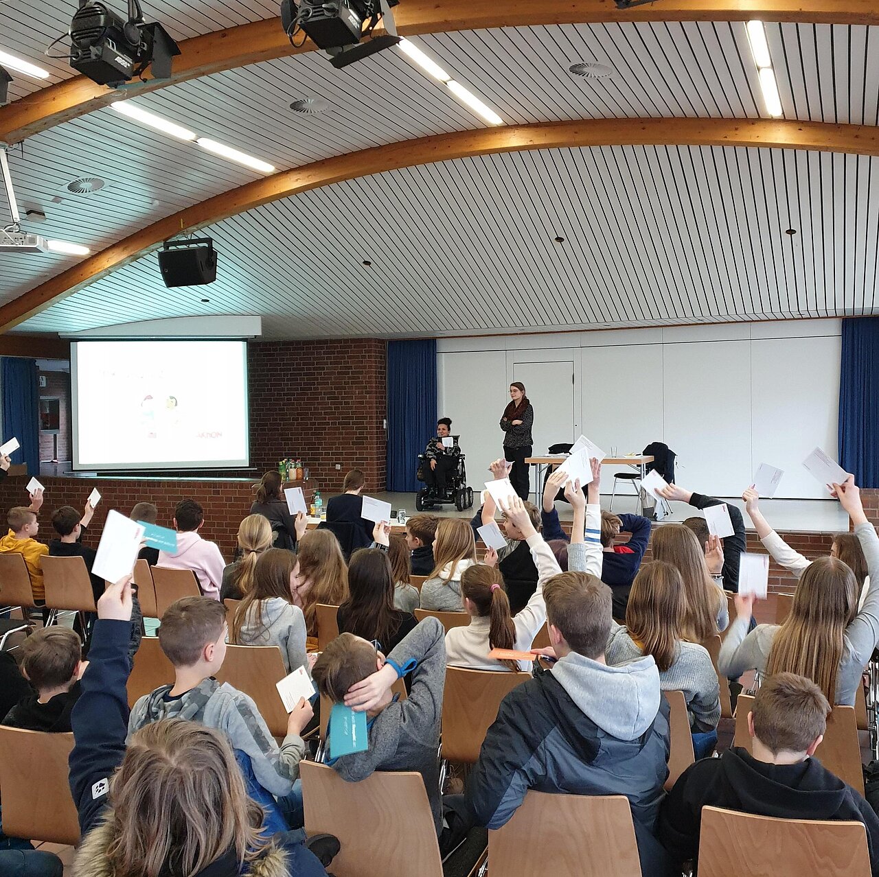 Jugendliche hören zu und heben Abstimmungskarten