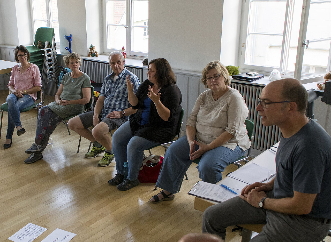 Das Bild zeigt eine Gruppe Menschen, die diskutiert