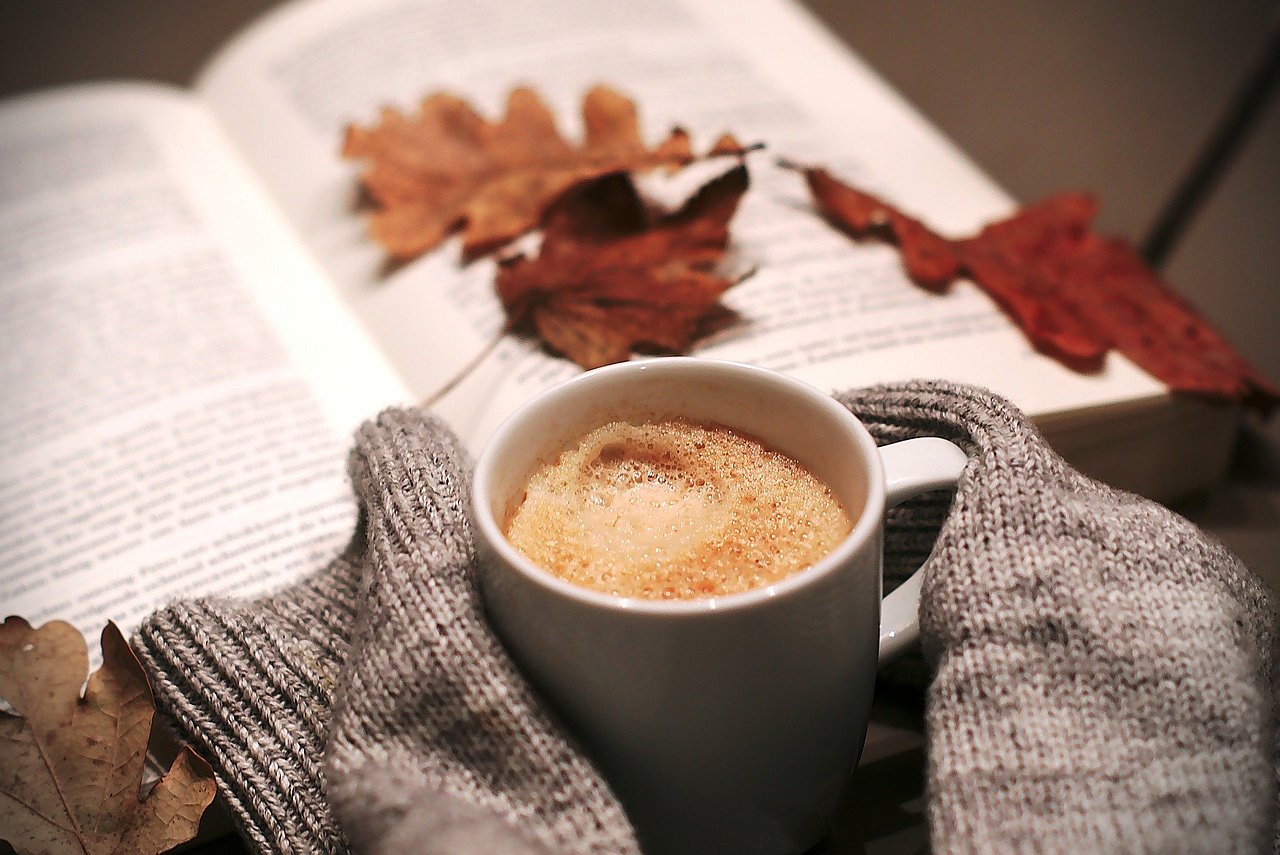 Bild von einer Kaffeetasse, einem Herbstblatt und warmen Socken