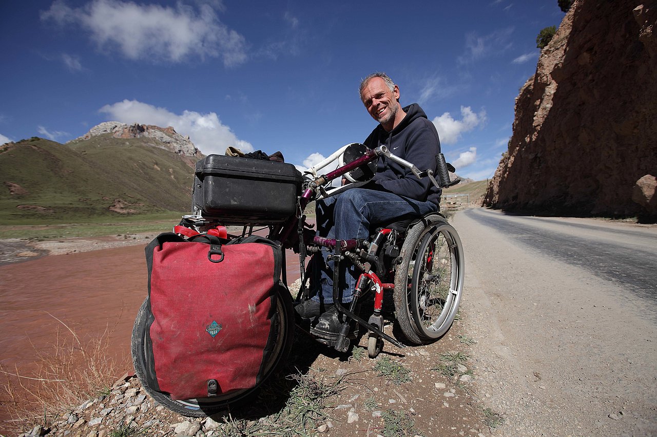 Foto von Andreas Pröve mit seinem Rollstuhl auf großer Reise.