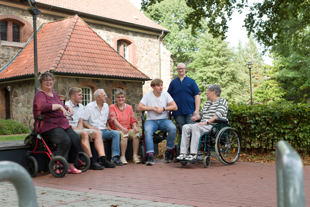 Foto von bunt gemischte Gruppe jüngerer und älterer Menschen mit und ohne Behinderung trifft sich draußen